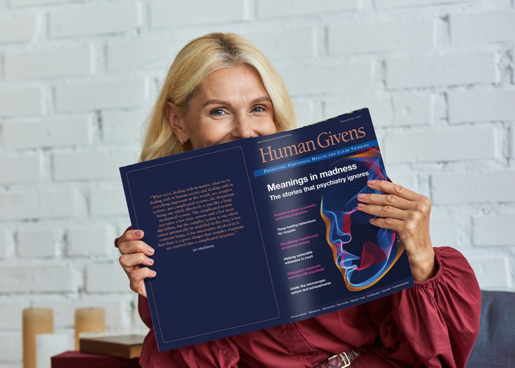 A woman holding up an issue of the Human Givens Journal, with the cover facing out