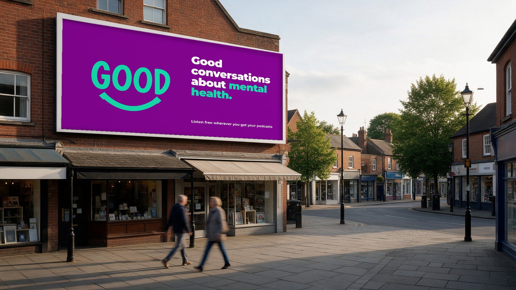 Concept: a purple billboard on a brick high-street building reading Good conversations about mental health, with the Good smile mark